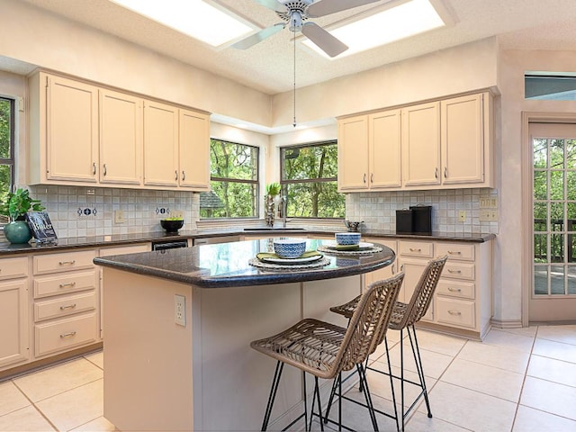 1400 Pearl Cv, Round Rock, TX 78681 - kitchen featuring light tile patterned floors, a kitchen bar, decorative backsplash, a center island, and ceiling fan
