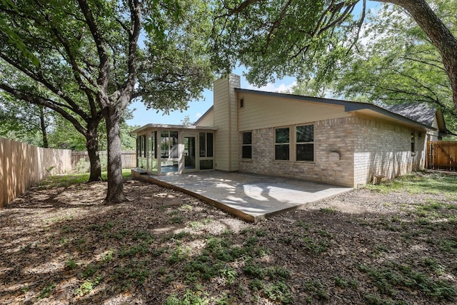 8507 Tad Park Cv, Round Rock, TX 78681 - rear view of house featuring a chimney, brick siding, a fenced backyard, a patio area, and a sunroom