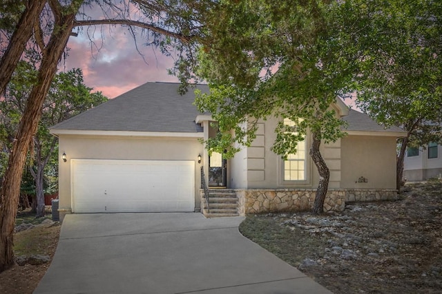 10 Lakewood Cir, Wimberley, TX 78676 - view of front of house featuring driveway, a garage, stucco siding, and stone siding