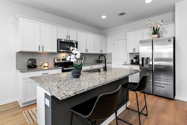 114 Ashford Way, Georgetown, TX 78626 - kitchen featuring appliances with stainless steel finishes, a sink, white cabinets, light wood-type flooring, and tasteful backsplash