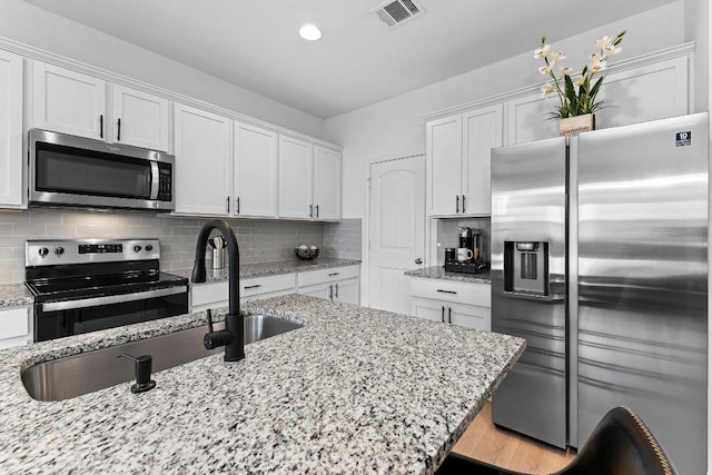114 Ashford Way, Georgetown, TX 78626 - kitchen featuring appliances with stainless steel finishes, white cabinets, a sink, decorative backsplash, and light stone counters