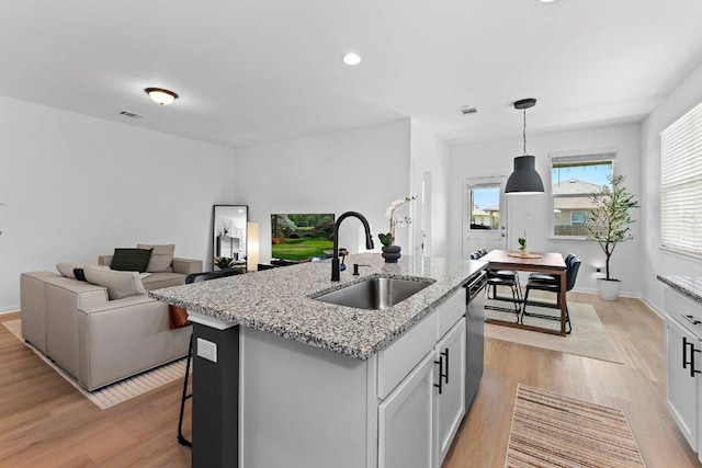 114 Ashford Way, Georgetown, TX 78626 - kitchen with a sink, stainless steel dishwasher, light wood-style floors, a center island with sink, and light stone countertops