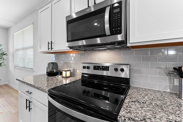 114 Ashford Way, Georgetown, TX 78626 - kitchen with stainless steel microwave, electric range oven, light stone countertops, backsplash, and white cabinetry