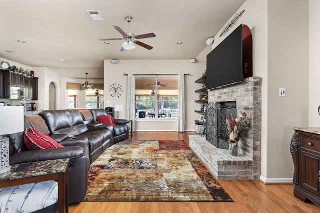 142 Abamillo Dr, Bastrop, TX 78602 - living room featuring ceiling fan, light wood-style floors, a fireplace, baseboards, and arched walkways