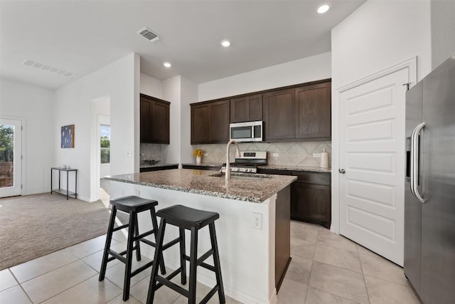 13002 Stanford Dr Unit 40, Austin, TX 78748 - kitchen with stainless steel appliances, light tile patterned floors, light colored carpet, dark stone countertops, and tasteful backsplash