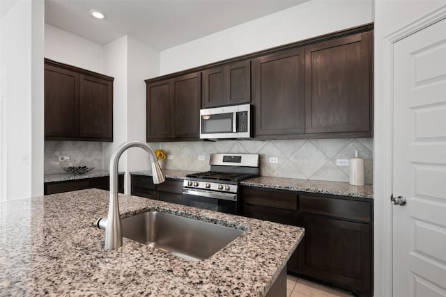 13002 Stanford Dr Unit 40, Austin, TX 78748 - kitchen featuring stainless steel appliances, dark brown cabinets, backsplash, light stone counters, and a sink