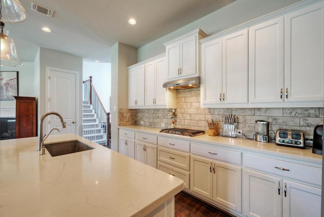 20304 Thumper Jack Ct, Pflugerville, TX 78660 - kitchen featuring a sink, under cabinet range hood, stainless steel gas cooktop, decorative backsplash, and recessed lighting