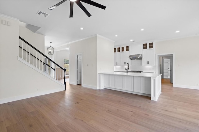 206 High Plains Dr, Dripping Springs, TX 78620 - unfurnished living room featuring ceiling fan, baseboards, stairway, light wood finished floors, and a sink