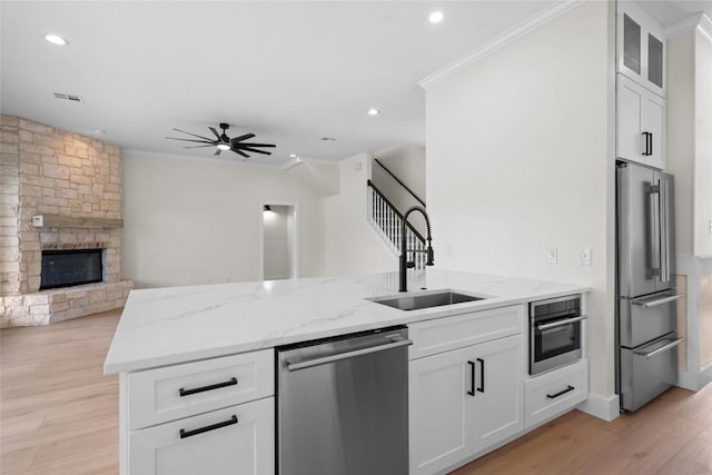 206 High Plains Dr, Dripping Springs, TX 78620 - kitchen featuring stainless steel appliances, a sink, crown molding, a ceiling fan, and a stone fireplace