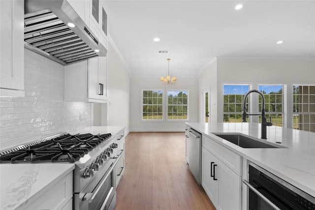 206 High Plains Dr, Dripping Springs, TX 78620 - kitchen featuring appliances with stainless steel finishes, wall chimney range hood, a sink, crown molding, and a chandelier