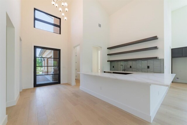 125 Azalea Loop, Horseshoe Bay, TX 78657 - entrance foyer with light wood finished floors, a towering ceiling, baseboards, and a chandelier