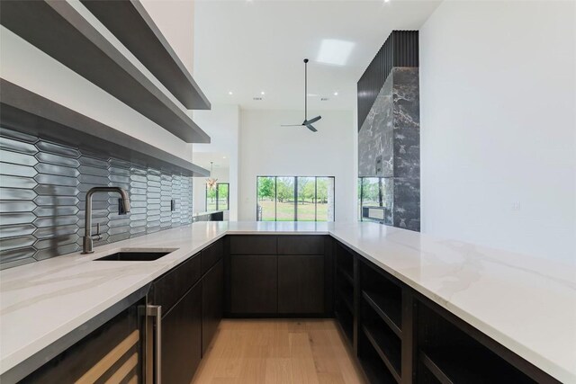 125 Azalea Loop, Horseshoe Bay, TX 78657 - kitchen with wine cooler, light stone countertops, a sink, light wood-type flooring, and tasteful backsplash