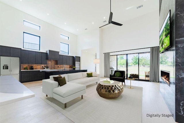 125 Azalea Loop, Horseshoe Bay, TX 78657 - living area with a high ceiling, ceiling fan, a lit fireplace, light wood finished floors, and plenty of natural light