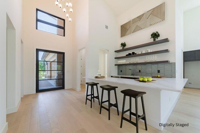125 Azalea Loop, Horseshoe Bay, TX 78657 - bar area with light wood-type flooring, a high ceiling, baseboards, and backsplash