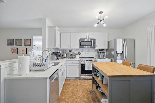 16708 Hamilton Point Cir, Manor, TX 78653 - kitchen with stainless steel appliances, wooden counters, a sink, tasteful backsplash, and white cabinetry
