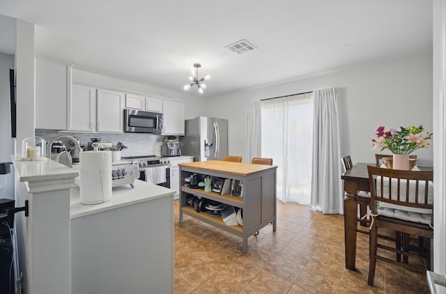 16708 Hamilton Point Cir, Manor, TX 78653 - kitchen featuring appliances with stainless steel finishes, light countertops, a chandelier, tasteful backsplash, and white cabinets