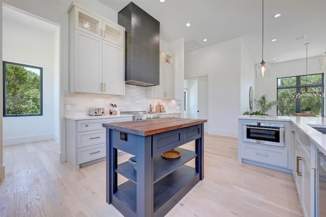 4255 Fm 3405, Georgetown, TX 78633 - kitchen with butcher block counters, wall chimney range hood, decorative backsplash, light wood-style flooring, and recessed lighting