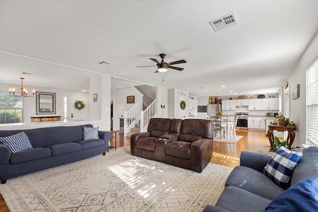 100 N Prairie Ln, Georgetown, TX 78633 - living area featuring light wood-type flooring, stairs, a ceiling fan, and a chandelier