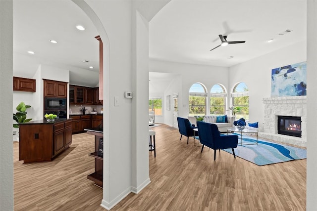 270 Harris Dr, Austin, TX 78737 - living room featuring ceiling fan, light wood finished floors, a stone fireplace, arched walkways, and recessed lighting