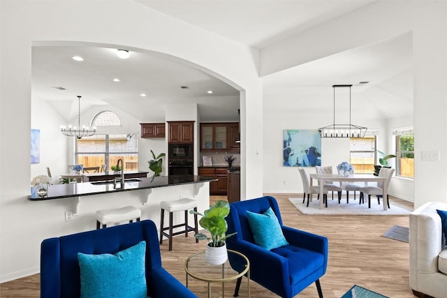 270 Harris Dr, Austin, TX 78737 - living room featuring a chandelier, vaulted ceiling, light wood finished floors, arched walkways, and baseboards