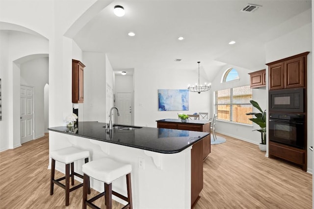 270 Harris Dr, Austin, TX 78737 - kitchen featuring black appliances, a sink, arched walkways, a peninsula, and light wood-type flooring