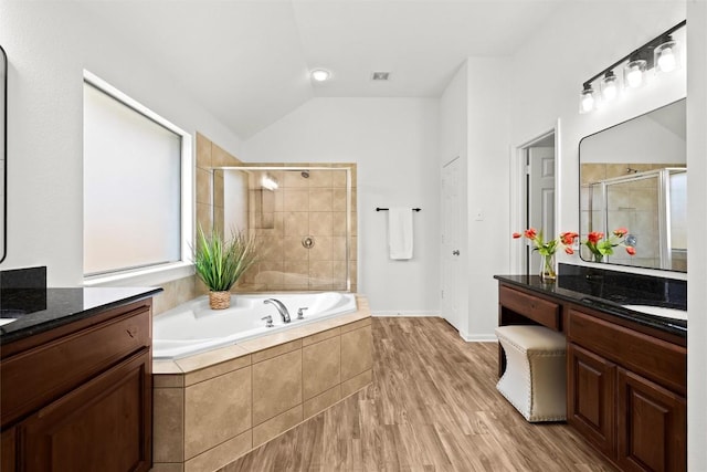 270 Harris Dr, Austin, TX 78737 - full bathroom featuring two vanities, vaulted ceiling, a stall shower, a bath, and wood finished floors
