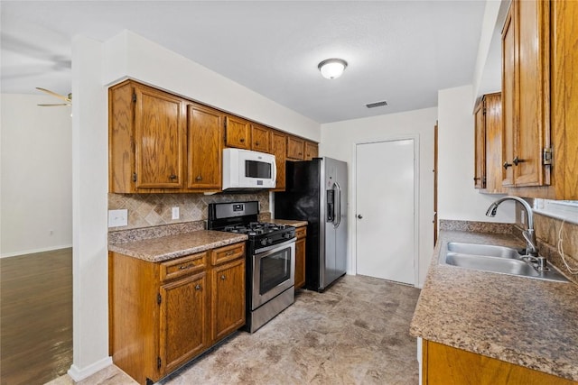 1404 Troy Ln, Round Rock, TX 78664 - kitchen with appliances with stainless steel finishes, a sink, brown cabinets, decorative backsplash, and baseboards