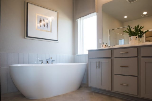 813 Vaughn St, Georgetown, TX 78628 - full bathroom featuring double vanity, a soaking tub, a shower with door, a wainscoted wall, and tile patterned floors