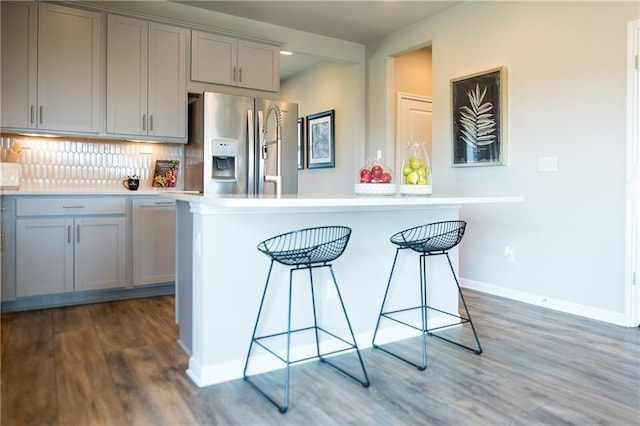 813 Vaughn St, Georgetown, TX 78628 - kitchen with stainless steel fridge with ice dispenser, gray cabinets, dark wood-style floors, a breakfast bar area, and recessed lighting