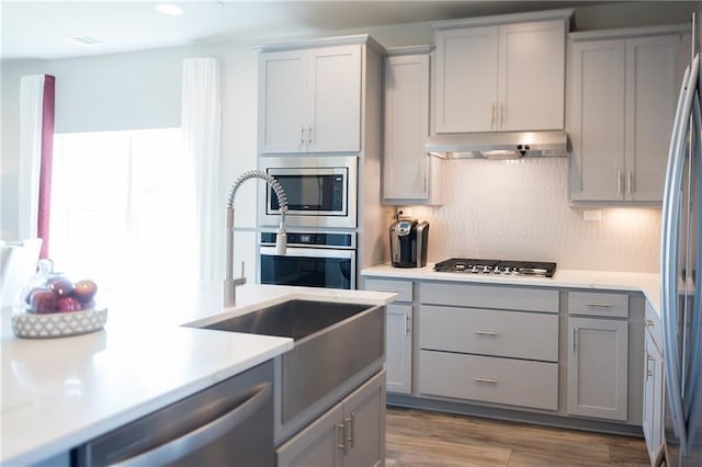 813 Vaughn St, Georgetown, TX 78628 - kitchen with gray cabinets, stainless steel appliances, under cabinet range hood, and light countertops