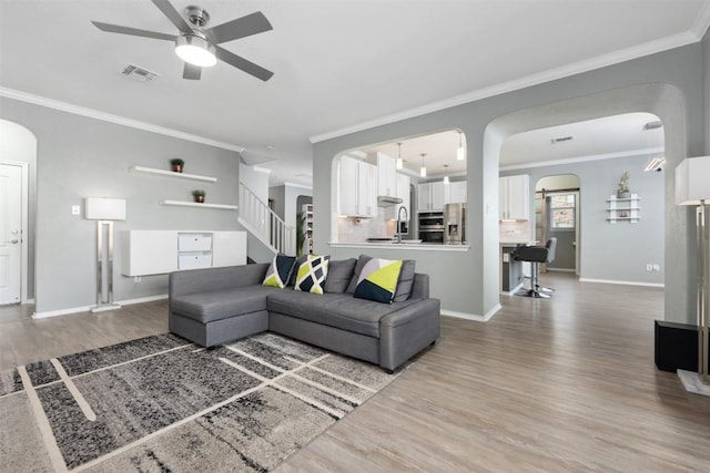 1312 Backcountry Dr, Leander, TX 78641 - living room featuring a ceiling fan, wood finished floors, baseboards, arched walkways, and crown molding