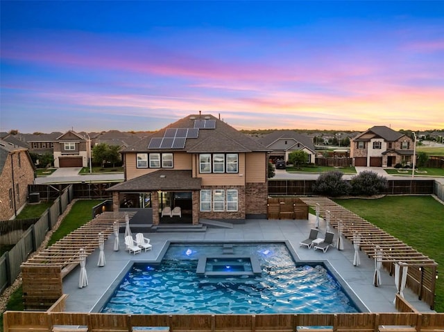 1312 Backcountry Dr, Leander, TX 78641 - back of property at dusk featuring roof mounted solar panels, a residential view, a patio, and a pool with connected hot tub
