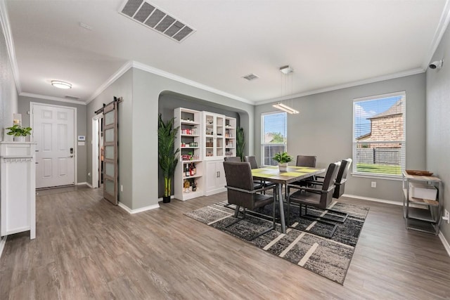 1312 Backcountry Dr, Leander, TX 78641 - dining space featuring ornamental molding, wood finished floors, a barn door, and baseboards