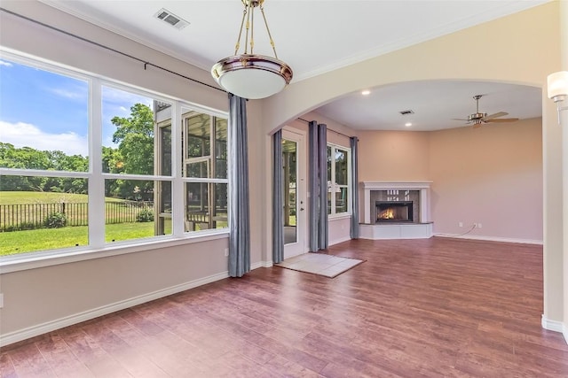 unfurnished living room featuring arched walkways, a ceiling fan, wood finished floors, baseboards, and recessed lighting