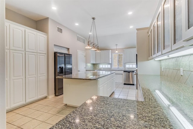 kitchen with refrigerator with ice dispenser, stainless steel dishwasher, backsplash, light tile patterned flooring, and dark stone counters