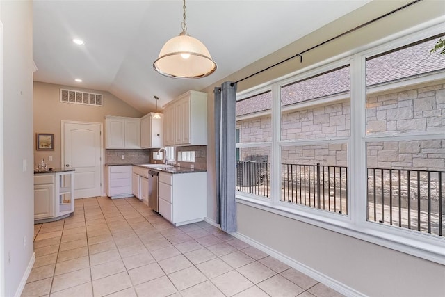 kitchen featuring light tile patterned floors, lofted ceiling, a sink, tasteful backsplash, and hanging light fixtures