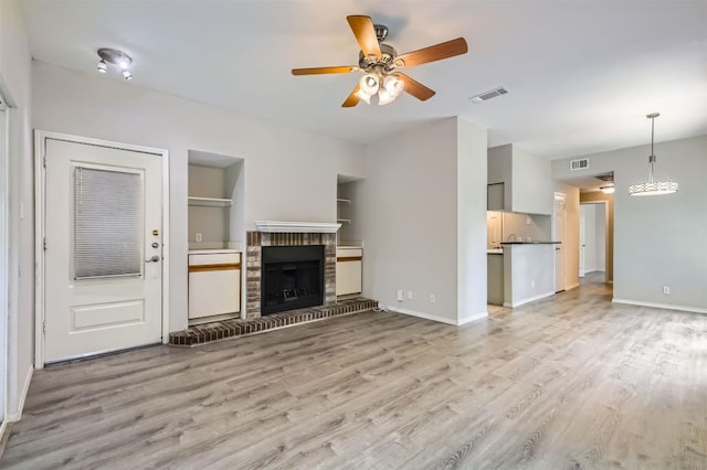 700 S 1st St S Unit 101, Austin, TX 78704 - unfurnished living room with light wood-style floors, ceiling fan, a brick fireplace, baseboards, and built in shelves