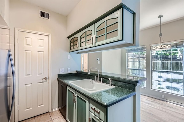 700 S 1st St S Unit 101, Austin, TX 78704 - kitchen with green cabinetry, a sink, freestanding refrigerator, a peninsula, and dishwasher