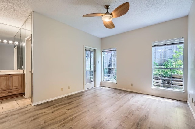 700 S 1st St S Unit 101, Austin, TX 78704 - empty room with light wood finished floors, a textured ceiling, ceiling fan, and baseboards