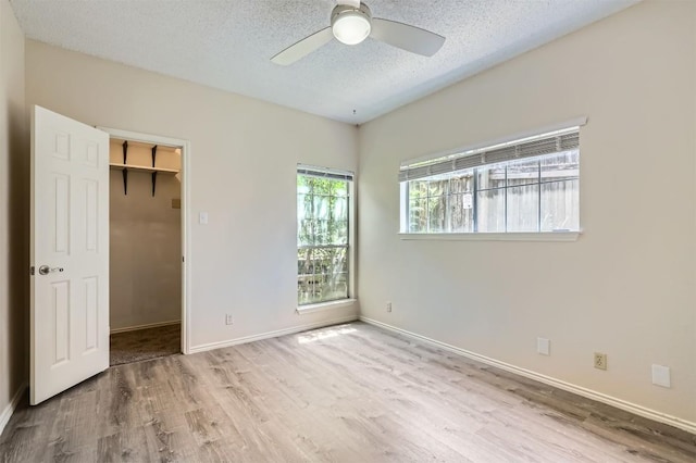700 S 1st St S Unit 101, Austin, TX 78704 - unfurnished bedroom with wood finished floors, a textured ceiling, a walk in closet, and baseboards