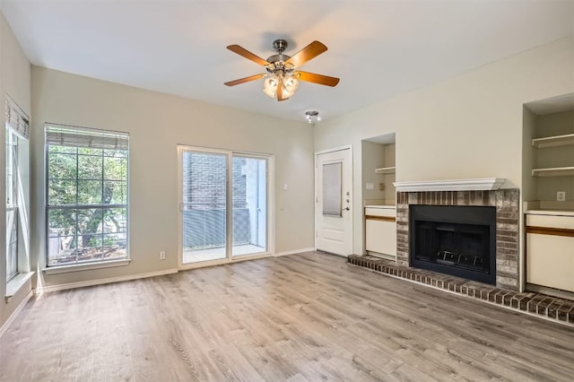 700 S 1st St S Unit 101, Austin, TX 78704 - unfurnished living room with wood finished floors, ceiling fan, a brick fireplace, baseboards, and built in features