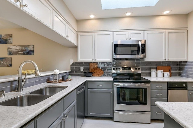 4117 Ridgeline Dr, Austin, TX 78731 - kitchen with appliances with stainless steel finishes, a sink, gray cabinets, backsplash, and a skylight