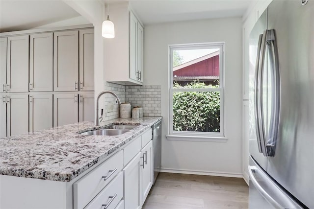 2603 Carlow Dr, Austin, TX 78745 - kitchen with appliances with stainless steel finishes, a sink, light wood-style flooring, light stone counters, and tasteful backsplash
