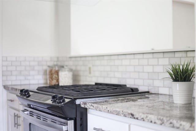 2603 Carlow Dr, Austin, TX 78745 - kitchen featuring stainless steel gas stove, white cabinets, tasteful backsplash, and light stone countertops