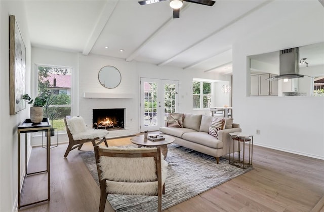 2603 Carlow Dr, Austin, TX 78745 - living area featuring a brick fireplace, beam ceiling, wood finished floors, ceiling fan, and french doors