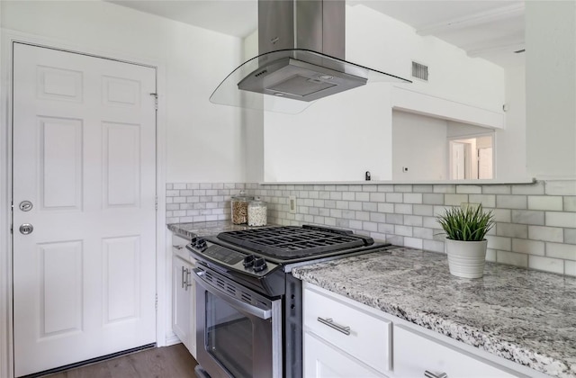 2603 Carlow Dr, Austin, TX 78745 - kitchen featuring stainless steel gas stove, island range hood, white cabinets, light stone counters, and tasteful backsplash