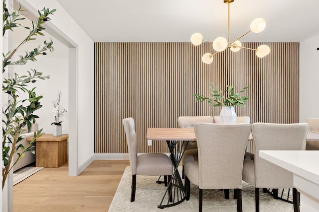 11008 Arch Ter, Austin, TX 78750 - dining area with an accent wall, a chandelier, wood finished floors, and baseboards