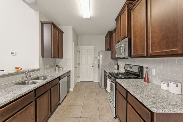 1701 S Bell Blvd Unit 101, Cedar Park, TX 78613 - kitchen with appliances with stainless steel finishes, a sink, decorative backsplash, light stone counters, and light tile patterned floors
