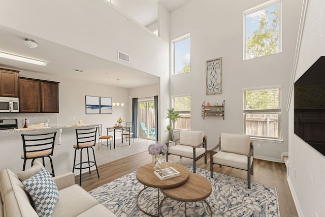 1701 S Bell Blvd Unit 101, Cedar Park, TX 78613 - living area with light wood-style floors, a chandelier, a high ceiling, and baseboards