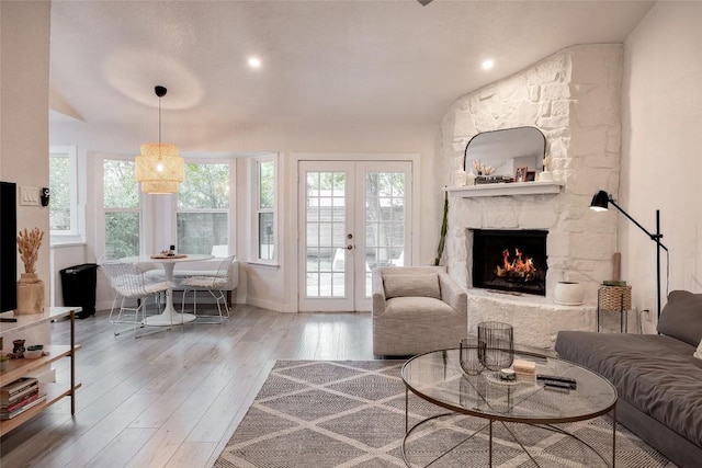 4601 Candletree Ln, Austin, TX 78744 - living room featuring wood finished floors, french doors, a stone fireplace, and baseboards